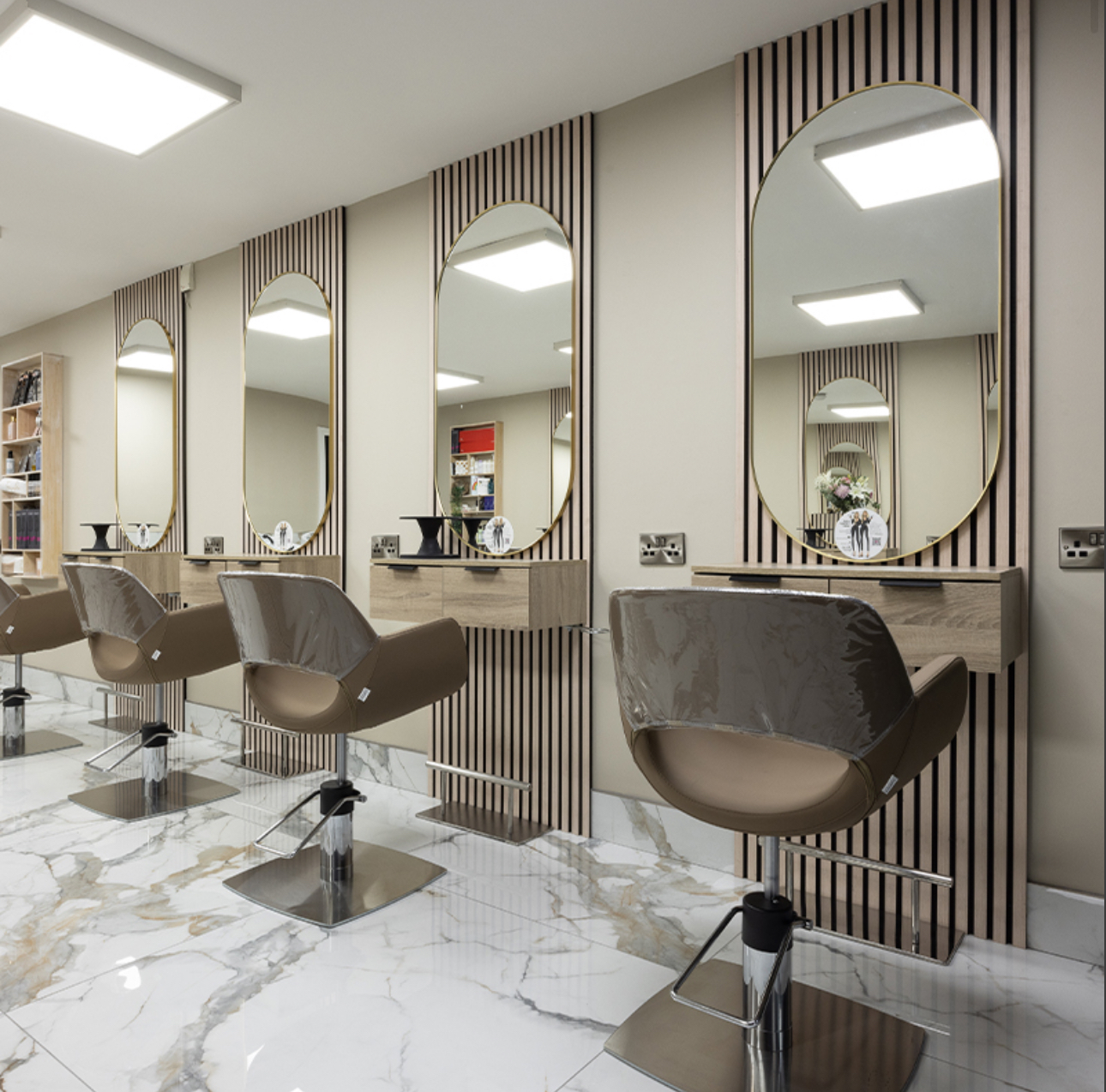 Completed beauty salon build-out with styling stations, oval mirrors and marble tile flooring