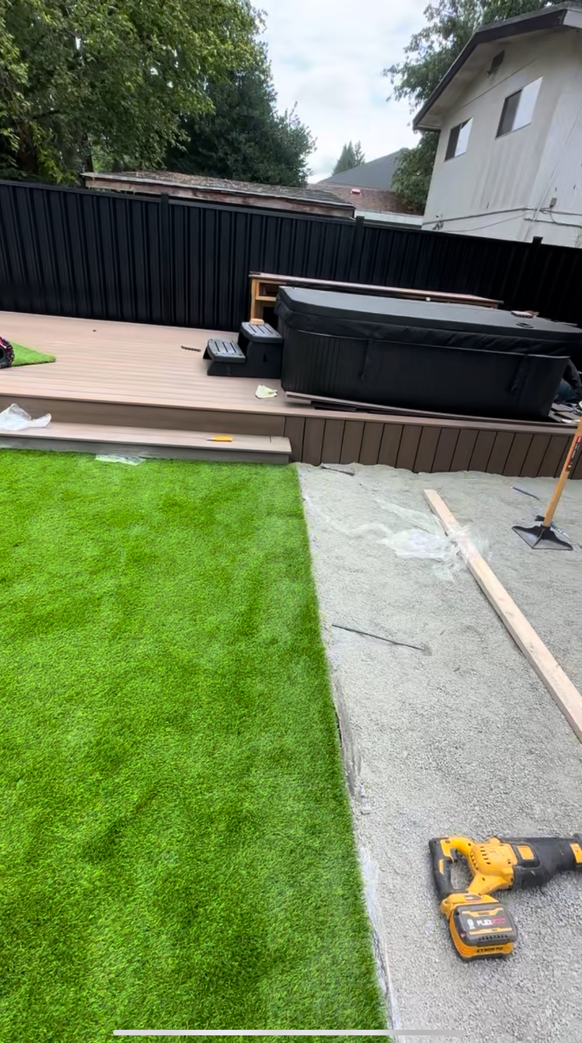 Artificial turf installation beside a composite deck and hot tub during a Port Coquitlam backyard project