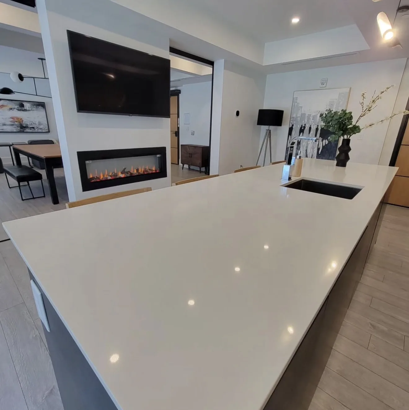 Renovated open-concept living space with quartz island, linear electric fireplace and wall-mounted TV