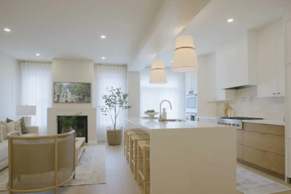Open plan kitchen and living area with an island, pendant lighting and white cabinetry