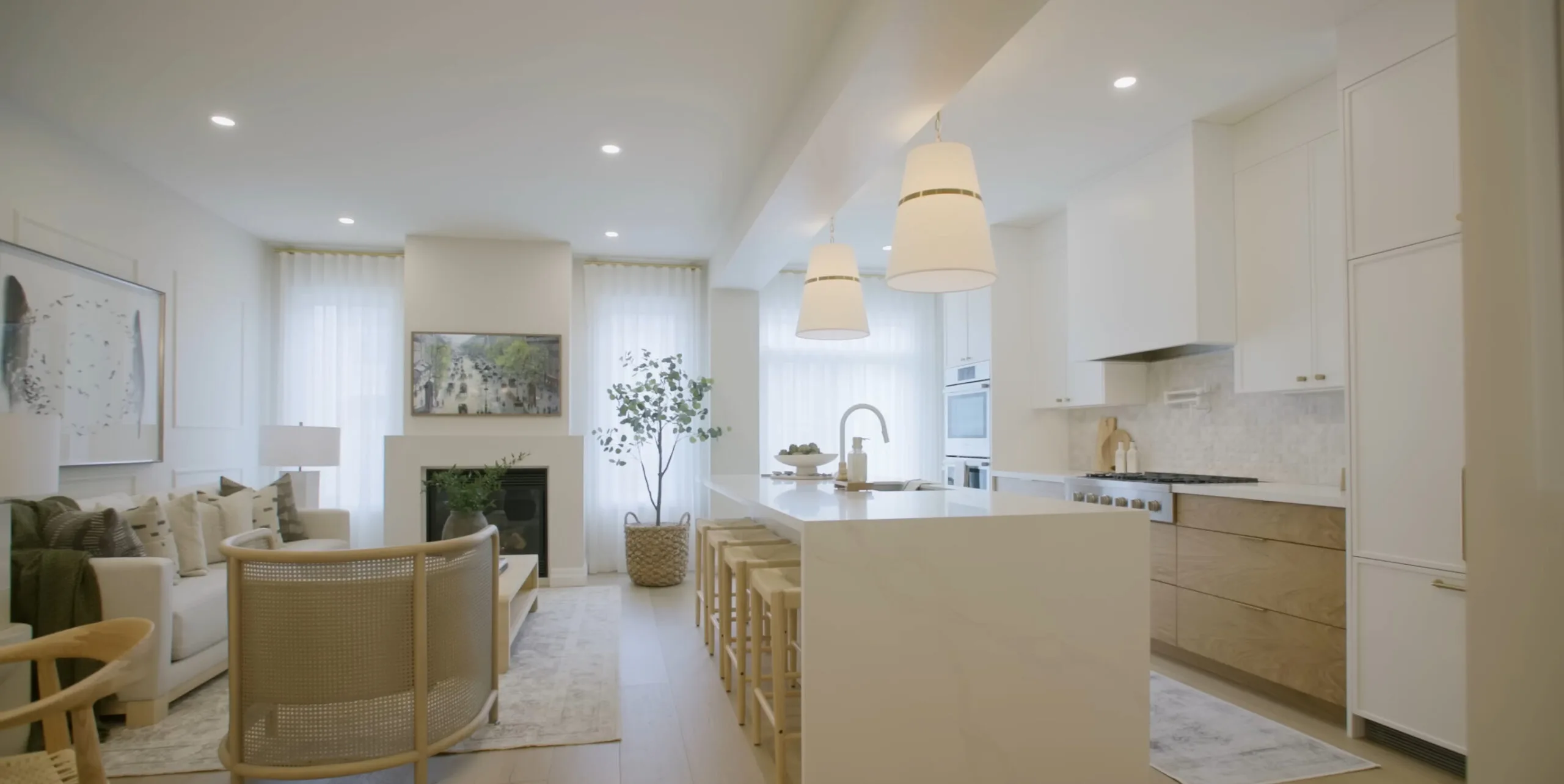 Open plan kitchen and living area with an island, pendant lighting and white cabinetry