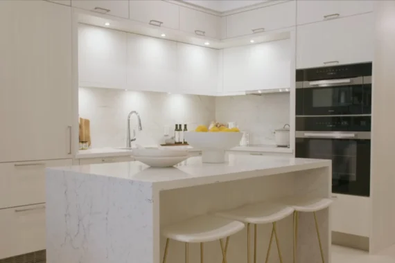 White kitchen with a stone island, double wall ovens and counter stools