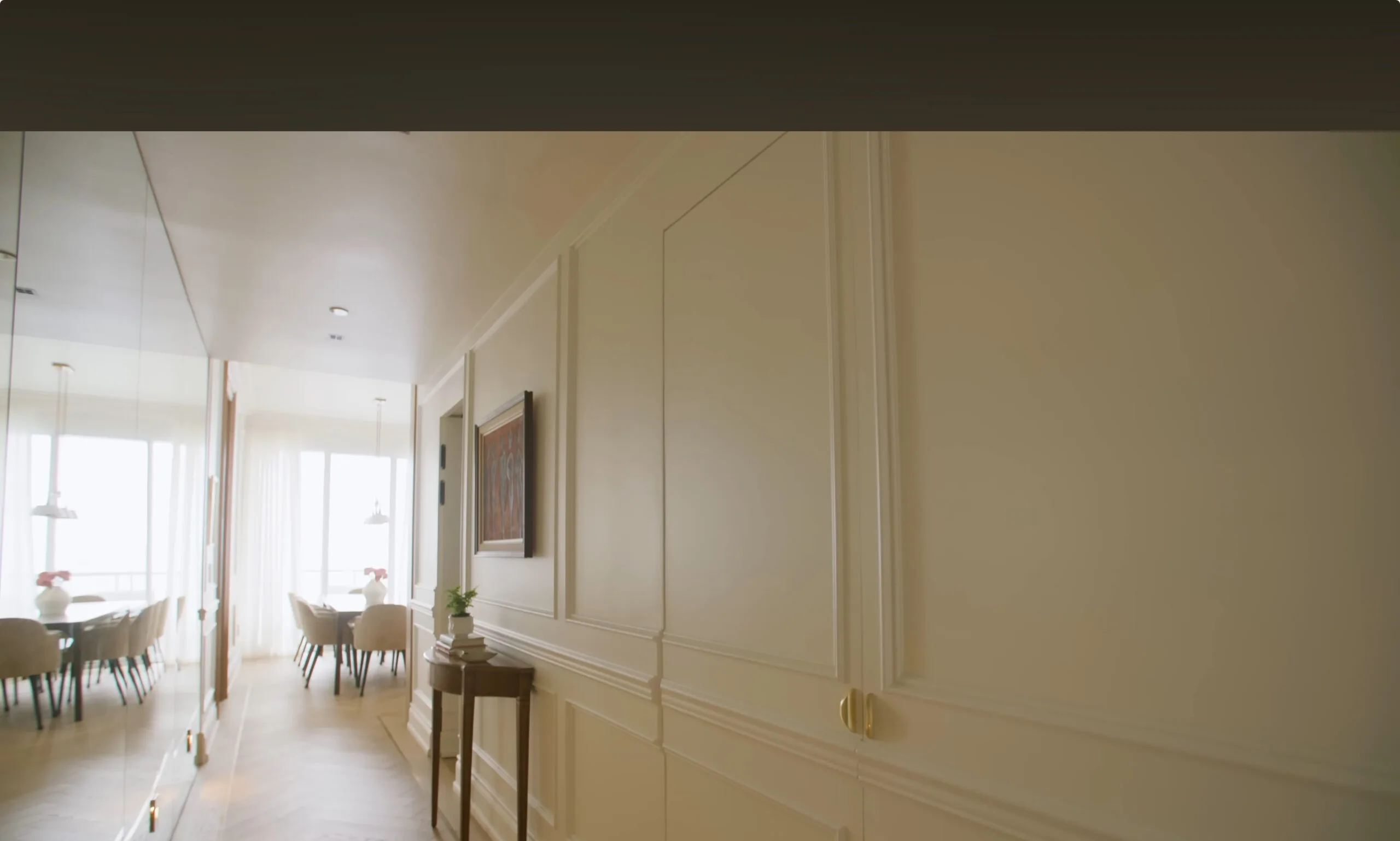 Hallway with cream panelled millwork, brass handles and a mirrored wall