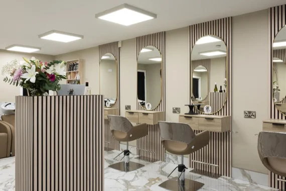 Salon interior with styling stations, arched mirrors and marble tile flooring